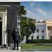 A police officer standing in front of a white house Description automatically generated