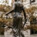 A statue of a person holding a sword and scales Description automatically generated