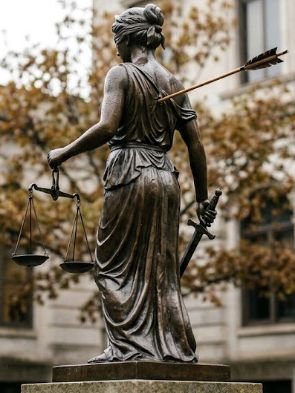 A statue of a person holding a sword and scales Description automatically generated